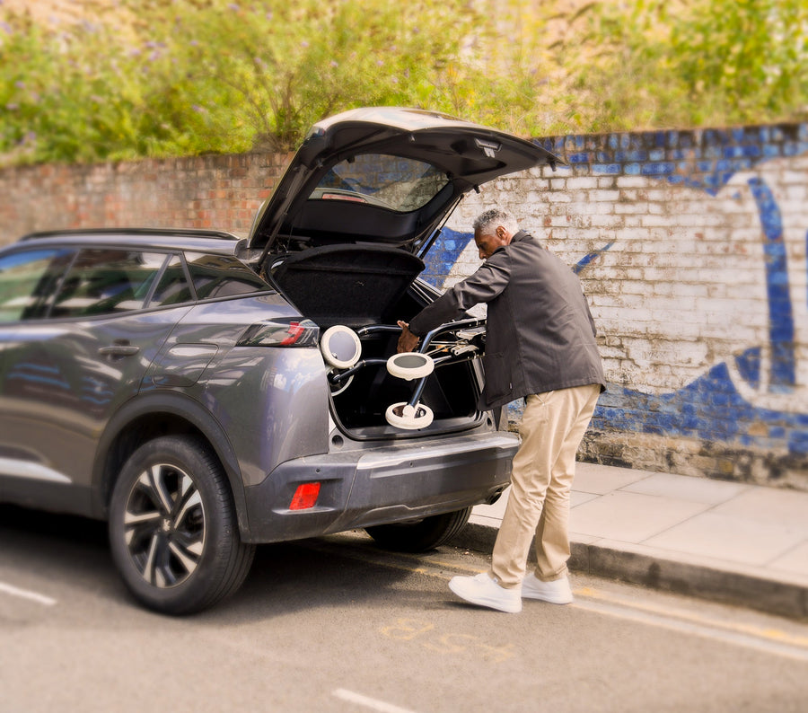 Man lifting the folded Zeal walker into a car boot